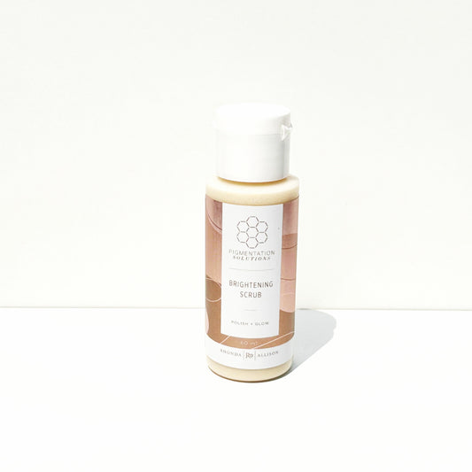 A bottle of Brightening Scrub with a white cap and a beige and brown label, set against a plain white background.
